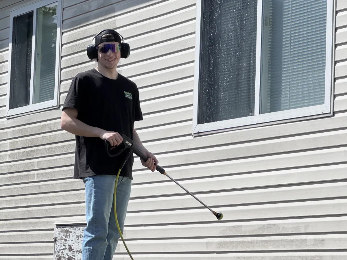 Joey, West Coast Landscaping crew member and University of Alberta goaltender, pressure-washing a Nanaimo home